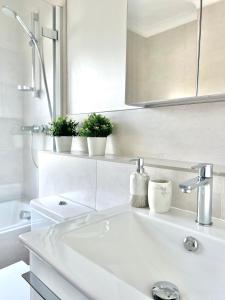 a white bathroom with a sink and three plants at BEAUTIFUL WINDSOR COTTAGE, AMAZING LOCATION, The Castle, Ascot, Legoland, Free Parking Super Close in Windsor