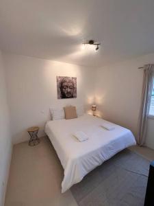 - une chambre dotée d'un grand lit blanc avec une photo sur le mur dans l'établissement Grand appartement a 300M de la plage, à Sainte-Maxime