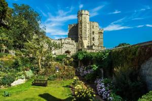 einen Garten mit einem Schloss im Hintergrund in der Unterkunft BEAUTIFUL WINDSOR COTTAGE, AMAZING LOCATION, The Castle, Ascot, Legoland, Free Parking Super Close in Windsor