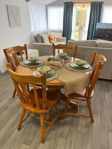 a dining room table with four chairs and a couch at Blackbrook Lodge Cabin in Turnditch