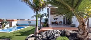 a villa with a swimming pool and palm trees at Villa Del Corazon Salinas Golf in Caleta De Fuste