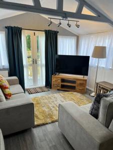 a living room with a flat screen tv and a couch at Blackbrook Lodge Cabin in Turnditch