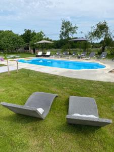 two lounge chairs in the grass near a swimming pool at Figtrees in Margueron