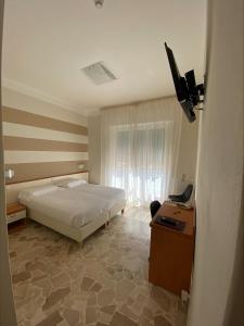 een slaapkamer met een bed, een bureau en een televisie bij Primavera in Levanto