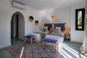 a bedroom with two beds and two chairs and a rug at Villa Al Assala Palmeraie in Marrakesh