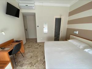 een slaapkamer met een bed, een bureau en een televisie bij Primavera in Levanto
