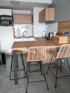 a kitchen with two bar stools and a counter top at Appartement aux Minimes in La Rochelle +2 photos