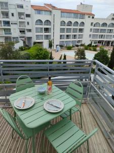 une table et des chaises vertes sur une terrasse avec des bâtiments dans l'établissement Appartement aux Minimes, à La Rochelle