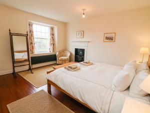 a bedroom with a large white bed and a fireplace at Covercote in Leyburn
