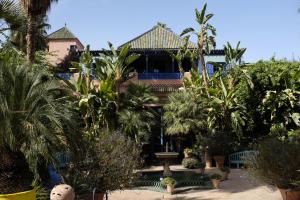 une maison avec des palmiers et une fontaine dans l'établissement RIAD TAZZORI, à Marrakech