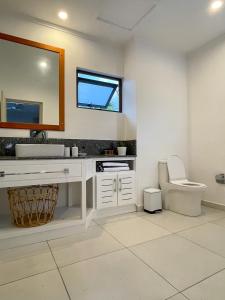 a bathroom with a toilet and a sink and a mirror at Nautilus Apartments in Mahe