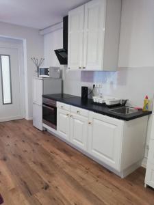 a kitchen with white cabinets and a black counter top at Appartement mit Terrasse in Metterzimmern