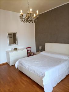 ein Schlafzimmer mit einem weißen Bett und einem Kronleuchter in der Unterkunft Casa Vacanze Litoranea in Follonica