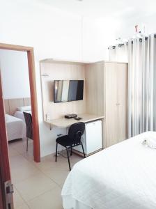 ein Hotelzimmer mit einem Schreibtisch und einem Bett in der Unterkunft Hotel San Gennaro in Santa Fé do Sul