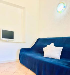 a blue couch with a white pillow on it at 20 steps from the beach VILLINO STECU in Costa Rei