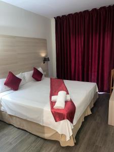 1 dormitorio con 1 cama blanca grande con almohadas rojas en Hotel Norai, en Lloret de Mar