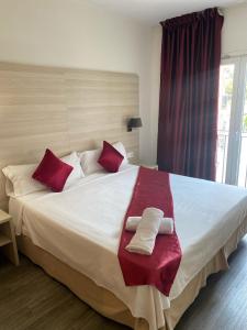 1 dormitorio con 1 cama grande con almohadas rojas y blancas en Hotel Norai, en Lloret de Mar