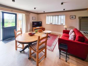 sala de estar con mesa y sofá rojo en Luxury Lodge @ Ewen Barn - private 5* retreat, en Cirencester