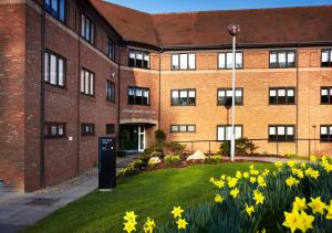 a brick building with yellow flowers in front of it at Peter Scott House Birmingham in Birmingham