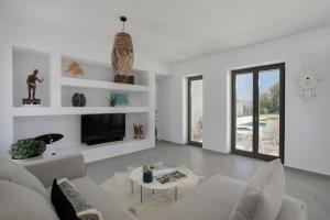 a white living room with a couch and a tv at STONE VILLA NAXOS in Naxos Chora