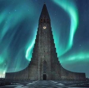 um grande edifício com uma torre de relógio sob a aurora boreal em Fox Hotel em Reykjavík