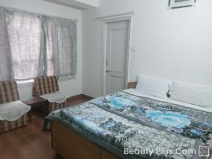 ein Schlafzimmer mit einem Bett, einem Stuhl und einem Fenster in der Unterkunft A1 B&B shimla in Shimla