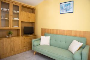 sala de estar con sofá verde y TV en RVHotels Apartamentos Els Salats, en L'Estartit