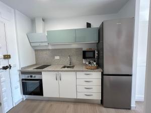 eine Küche mit weißen Schränken und einem Edelstahlkühlschrank in der Unterkunft Selvática Studio Torre del Mar in Torre del Mar