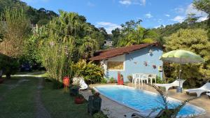 una casa azul con piscina en el patio en Pousada Jardim Secreto en Teresópolis