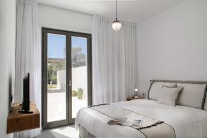 a white bedroom with a bed and a sliding glass door at STONE VILLA NAXOS in Naxos Chora