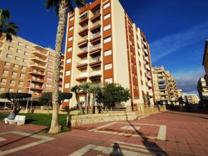 a tall building with palm trees in front of it at Frente al Mar con Garaje y Wifi - by Aloha Palma in Águilas