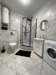 uma casa de banho branca com um chuveiro e uma máquina de lavar roupa em Квартира в новому ЖК Svitlo Park Київ em Kiev