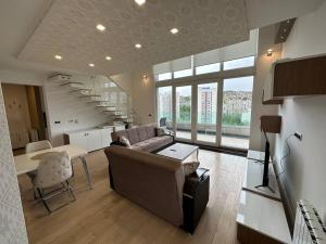 - un salon avec un canapé, une table et un escalier dans l'établissement Cityscape Penthouse, à Sarajevo