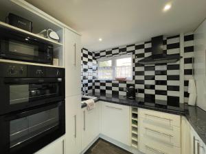 una cocina con azulejos blancos y negros en la pared en Quaint 2 Bed Village Retreat, en Pevensey