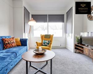 a living room with a blue couch and a table at Deluxe Apartment in Southend-On-Sea by Artisan Stays I Long Stay Offer I Relocation or Business in Southend-on-Sea