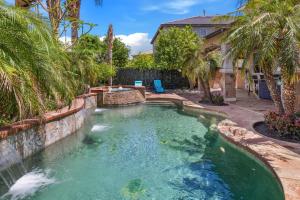 - une piscine avec une cascade dans une arrière-cour ornée de palmiers dans l'établissement Paradise private resort with waterfall pool, à Coachella