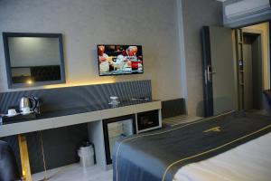 Habitación de hotel con cama y TV en la pared en Alfin Hotel, en Ankara