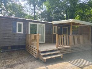 Cette grande cabane en bois dispose d'une terrasse couverte et d'escaliers. dans l'établissement Mobil home confort 6 personnes, à Saint-Chéron