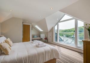 a bedroom with a large white bed with a large window at Lindos in Looe