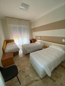 une chambre d'hôtel avec deux lits et une chaise dans l'établissement Primavera, à Levanto