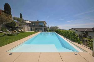 una grande piscina blu di fronte a una casa di Villa Madabà - Immobiliare Azzurra a Bardolino
