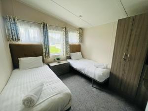 a room with two beds and a window at Moore Lodge with Hot Tub in Barmby on the Moor