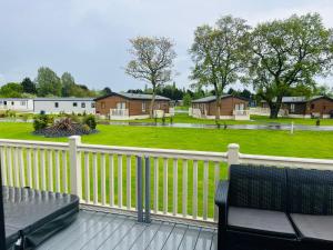 a porch with a white fence and a yard with houses at Moore Lodge with Hot Tub in Barmby on the Moor