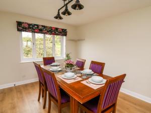 uma sala de jantar com uma mesa de madeira e cadeiras em Applecroft em Coreley
