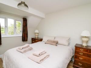 a bedroom with a white bed with two towels on it at Applecroft in Coreley