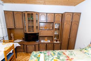 Habitación con armarios de madera y TV. en Studio apartman Ivana, en Gradište