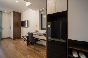 um quarto com uma secretária e uma cozinha com um frigorífico em Maison Vy Anh Hotel & Apartment em Da Nang