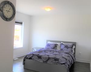 ein Schlafzimmer mit einem Bett mit lila Kissen und einer Uhr in der Unterkunft New Town House Barrie South in Barrie