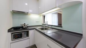 a white kitchen with a sink and a microwave at Citiresort Living sukhumvit 39 in Makkasan