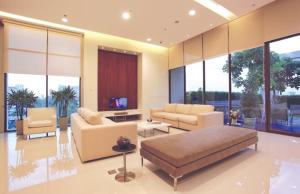 a living room with a couch and chairs and windows at Citiresort Living sukhumvit 39 in Makkasan